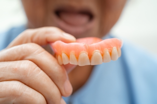 Close-up of a hand holding an upper full denture